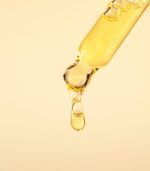 Cosmetic pipette with vitamin C serum or essential oil on light background. Skin care anti-aging treatment.